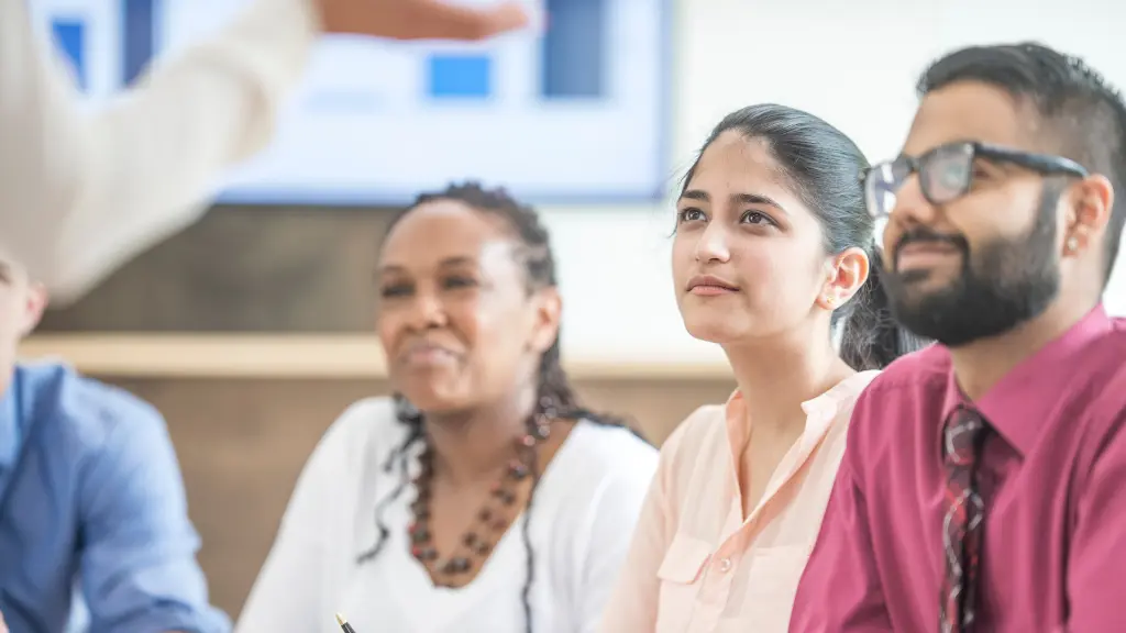 A group of people sitting down and being spoken to by a trainer. This is the picture for the article what is a trainer.