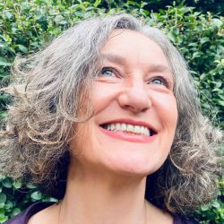 Smiling woman with gray curly hair looking upwards.